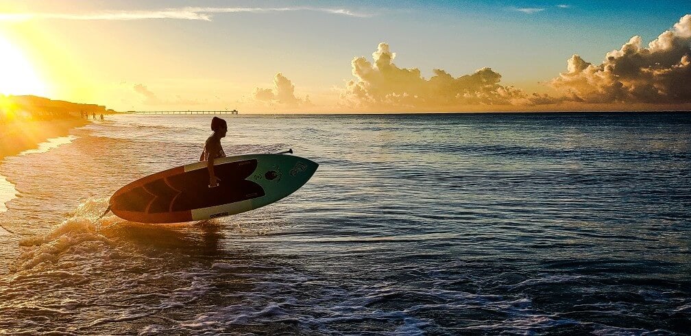Sober living resident wading into the surf at sunrise to start a morning surf session