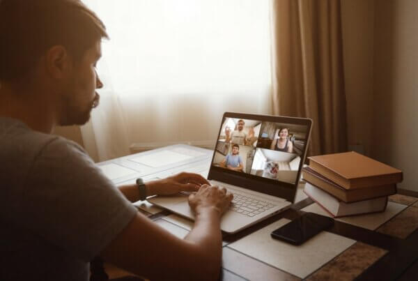 back view of man talking to his alcoholics anonymous friends online vs in person video conference