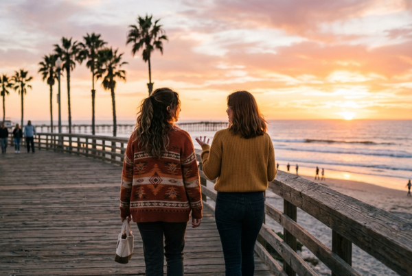 Two friends talking on the Pacific Beach boardwalk at sunset, illustrating openness in addiction stigma recovery