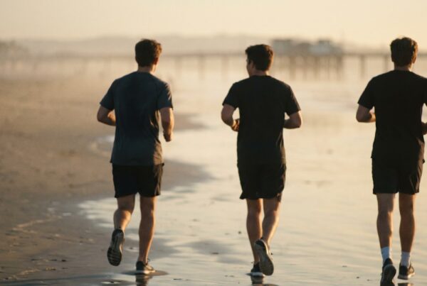 Men walking to a beach workout at sunrise near a San Diego men's sober living home